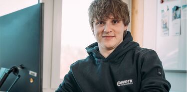 Ein junger Mann mit dem Logo ewerk Sachsenwald sitzt an einem Computer.