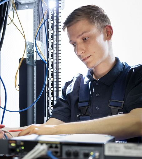 Ein junger Mann arbeitet konzentriert an einem elektrischen System.