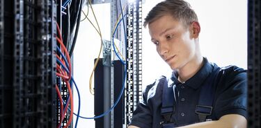 Ein junger Mann arbeitet konzentriert an einem elektrischen System.
